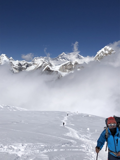 Snow-covered peaks under a cloudy blue sky.