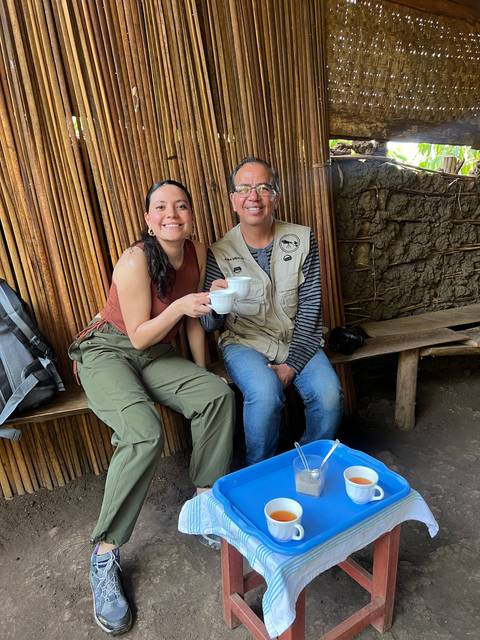 Two people sitting indoors with drinks on a blue tray.