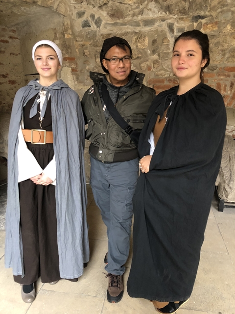 Three people wearing historical costumes standing indoors.
