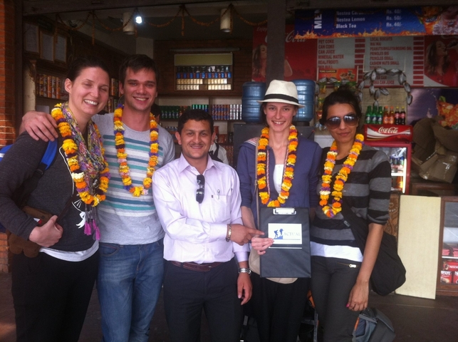       Group of people with flower garlands posing with a local person.
  