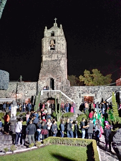       A stone church at night, surrounded by people.
  