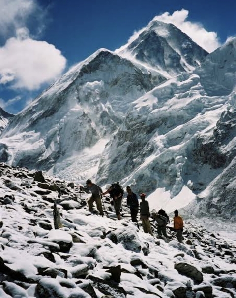 Group of people trekking on snowy mountain terrain.