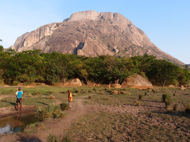       Two children standing in front of a rocky mountain landscape.
  