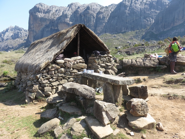       Stone hut with a thatched roof outdoors.
  