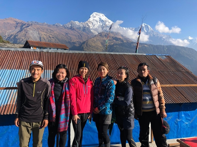       Group of people posing with snowy mountains behind.
  