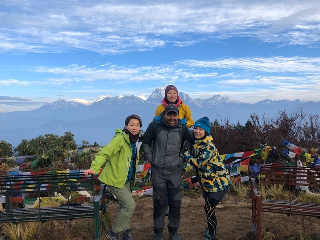       Smiling group with mountains in the background and prayer flags.
  