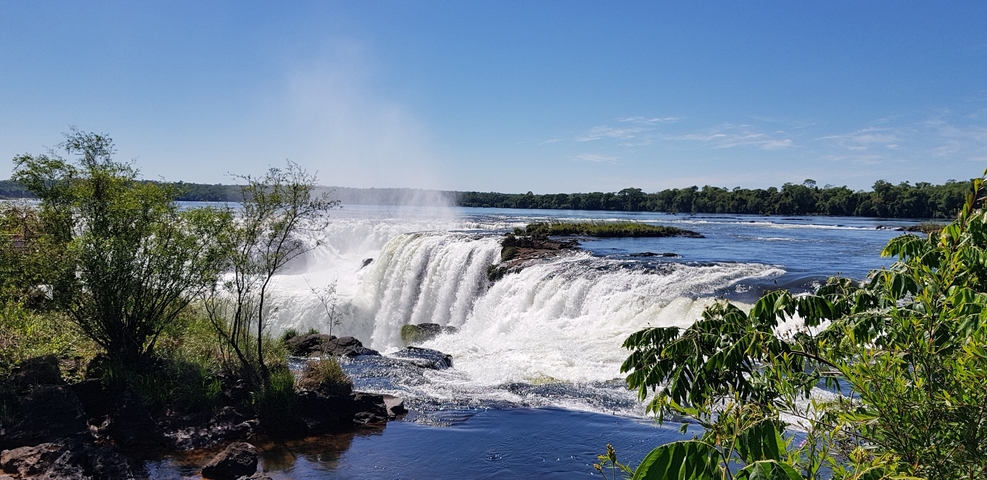 Close-up of Iguazu Falls with lush greenery and mist from the waterfall.
