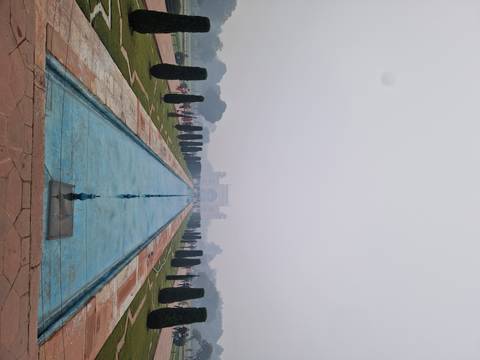       A long water channel in a garden facing a structure in the distance.
  