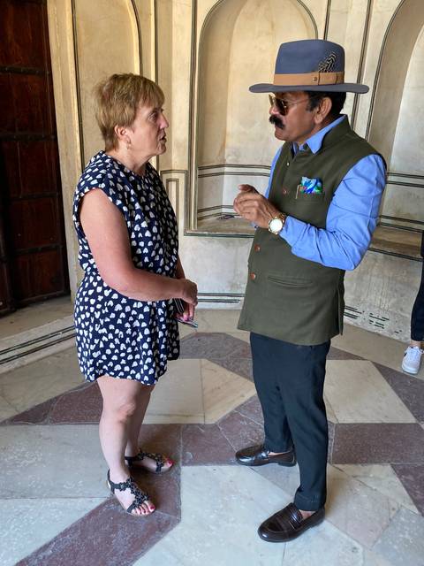       Two people in conversation, lady in patterned dress.
  