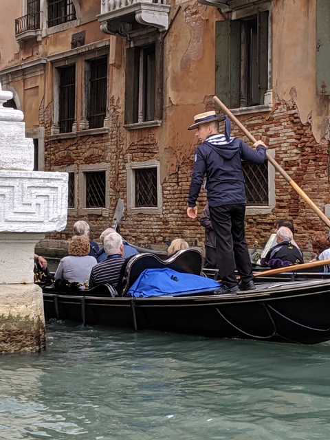 Gondolier steering tourists down a Venetian canal.