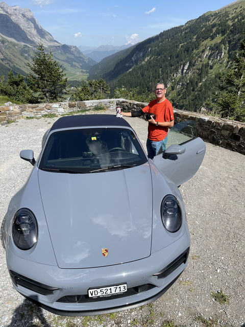 Man cleaning a luxury sports car in a mountainous area.