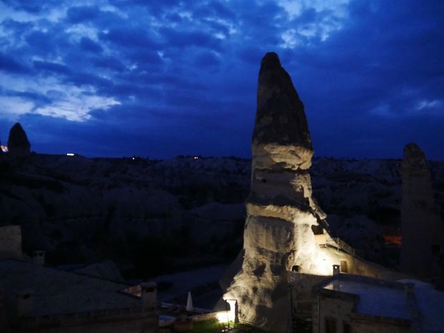       Lit rock formations at night under a deep blue sky.
  