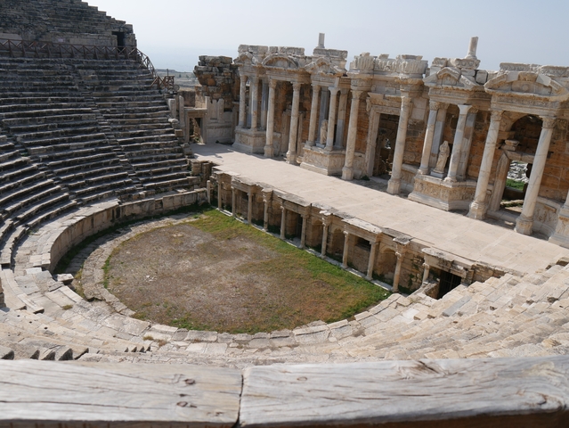       Ruins of an ancient amphitheater with stone seating and columns.
  
