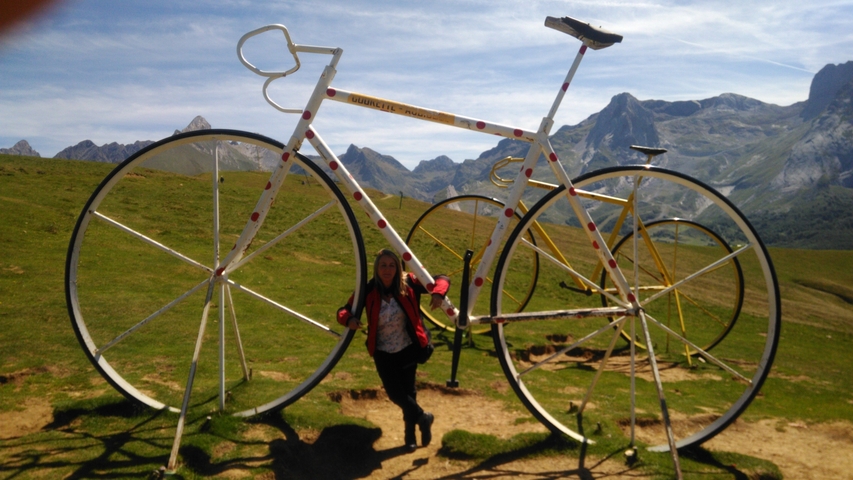       A person next to giant bicycle sculptures in the mountains.
  