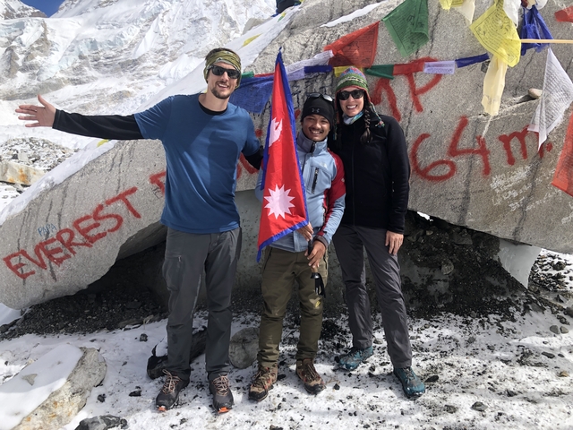       Three hikers with a Nepal flag at Everest Base Camp.
  