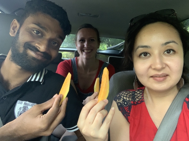 Three people inside a car holding slices of fruit.
