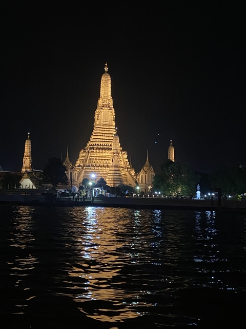       Illuminated temple at night by a river.
  