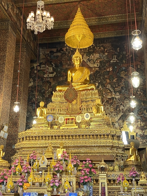       Golden Buddha statue inside a richly decorated temple.
  