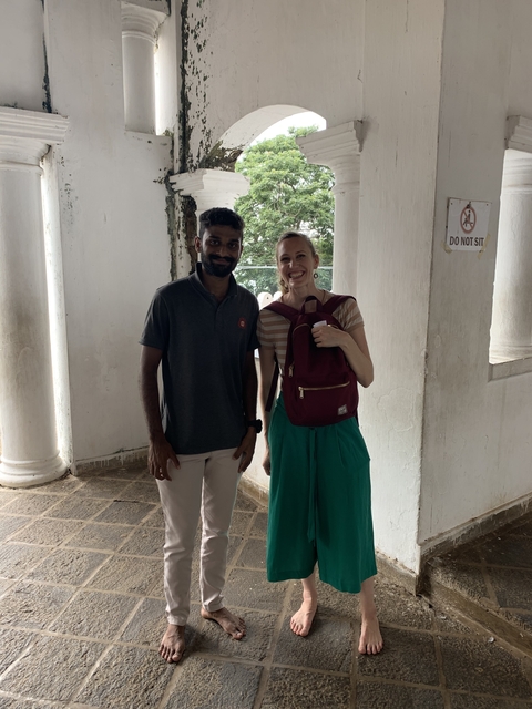       Two people standing in an outdoor setting with columns.
  