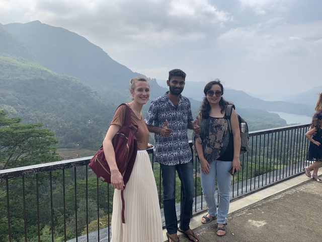 Three people posing with a scenic mountain view.