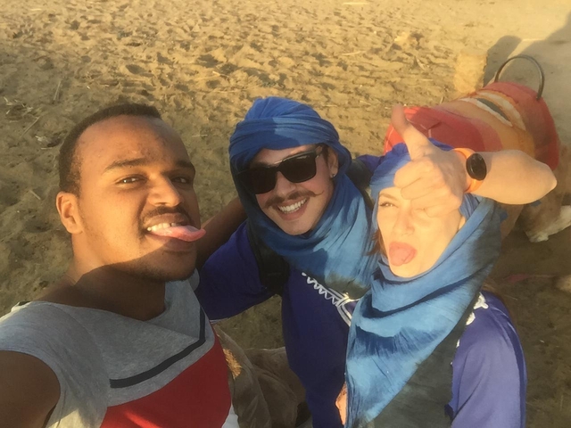 Three people wearing traditional headscarves posing for a selfie.