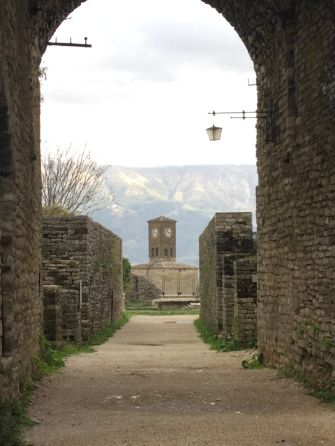      Clock tower viewed through ancient stone walls.
  