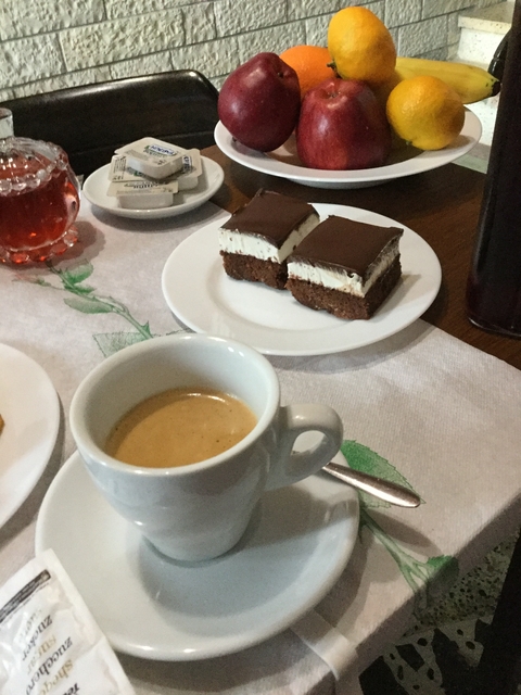       Cup of coffee with small dessert items on a plate.
  