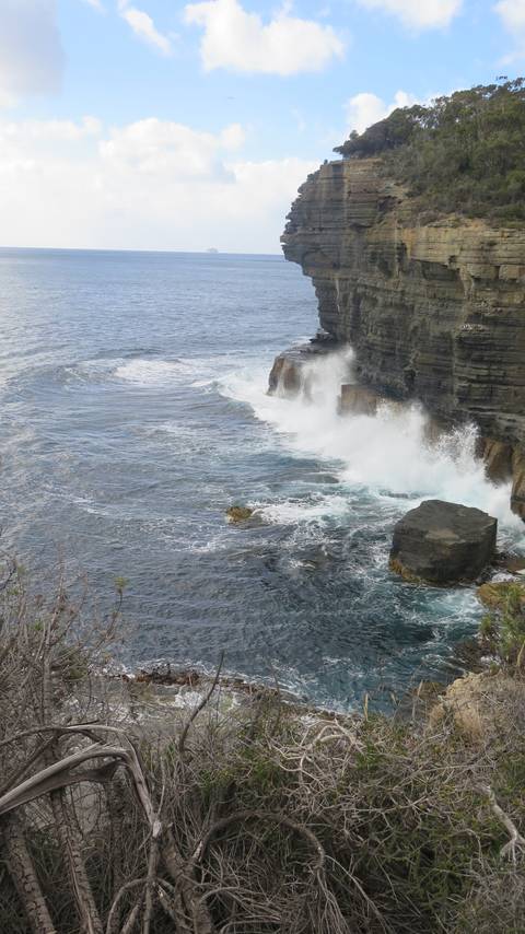 Coastal rock formation with ocean waves crashing against it.