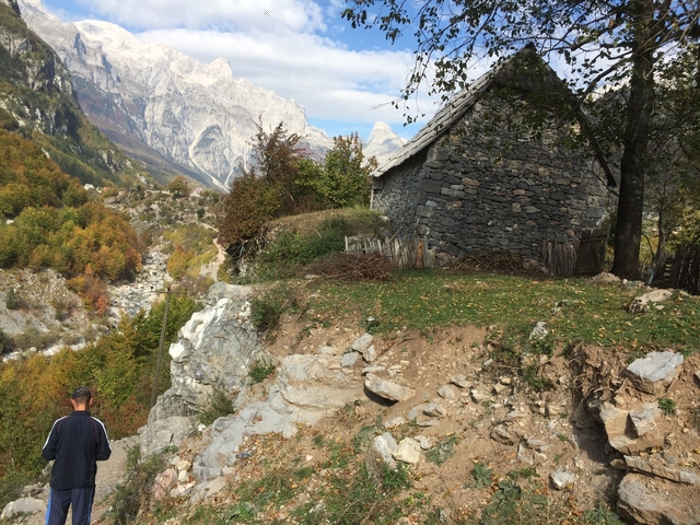 Stone house in a rural mountainous area with a person walking.