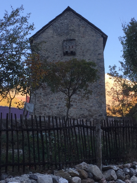 Stone building with a fence and mountain in the background.
