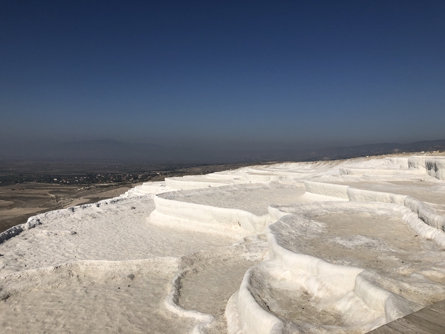       Panoramic view of Pamukkale's white terraces under clear blue sky.
  