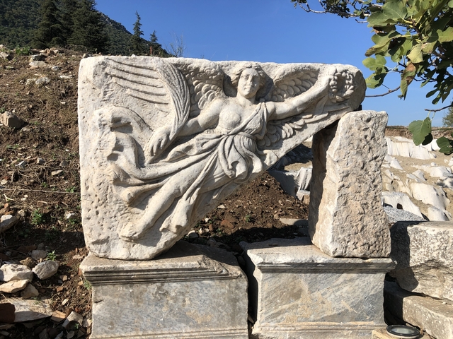       Ancient carved stone relief of a winged figure.
  