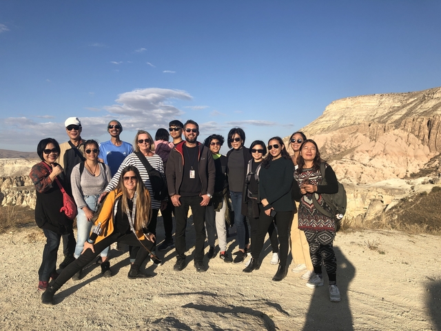       Group posing on a rocky landscape with blue skies.
  