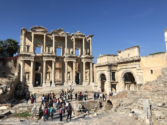       Ruins of the Library of Celsus with tourists walking around.
  