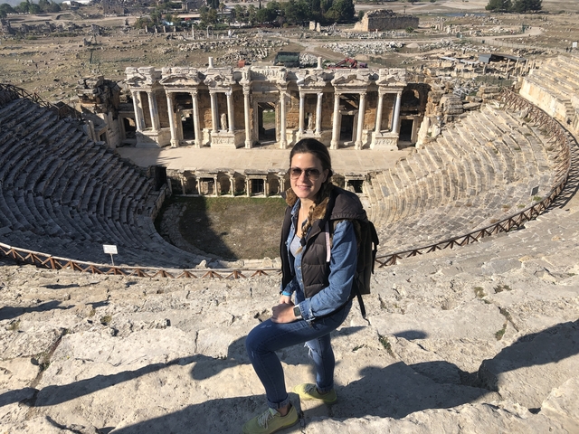       Woman sitting in front of ancient amphitheater ruins.
  