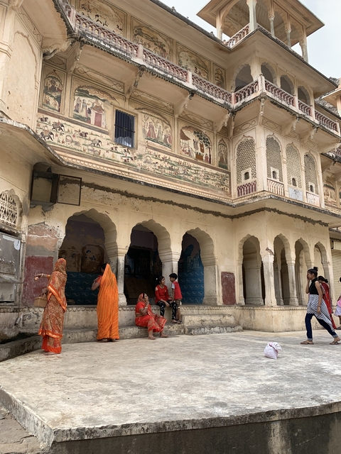       People sitting in front of ornate pillars and fresco.
  