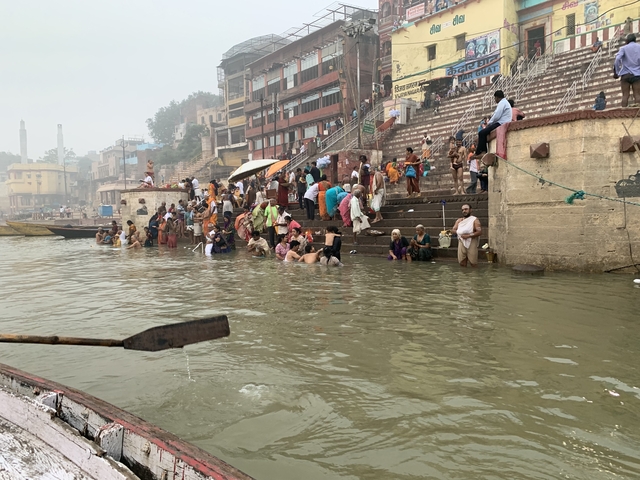       People performing rituals and bathing at the ghats.
  