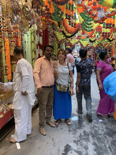       Street market scene with people and colorful flowers.
  