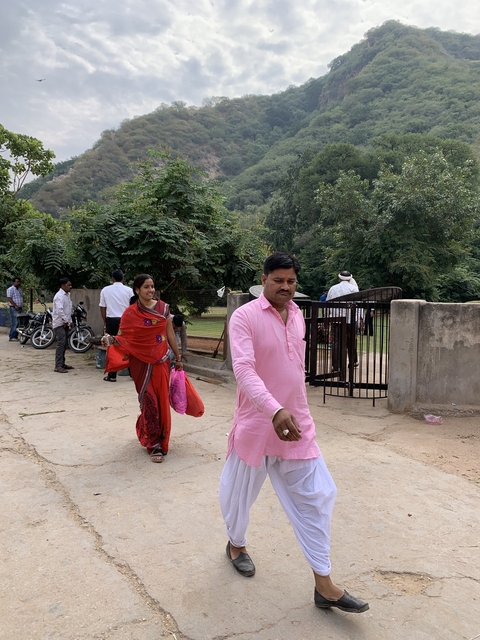       People walking in a park-like area with greenery.
  
