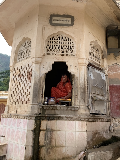       Woman sitting by a window of an old building.
  
