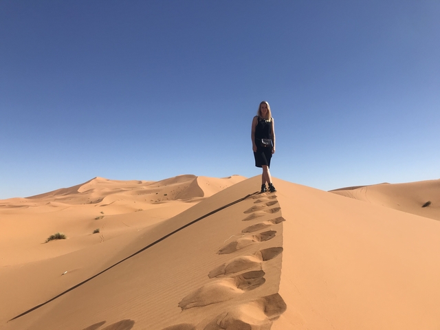       Woman standing on sand dunes in a desert landscape.
  