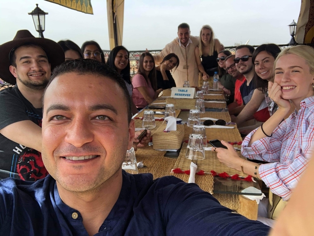       Group of people seated at a long table enjoying a meal.
  