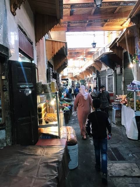       Busy market scene with people shopping and selling goods.
  