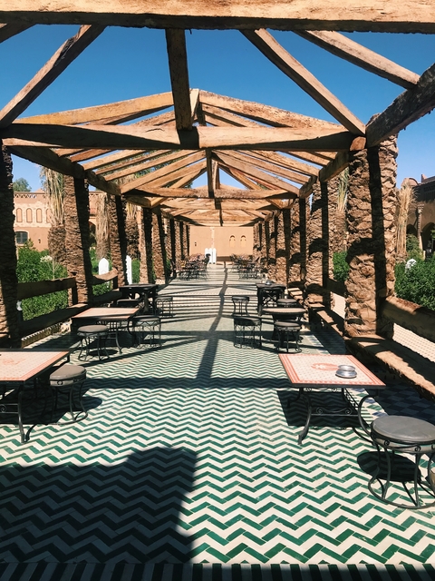       Outdoor cafe with empty tables and decorative flooring.
  