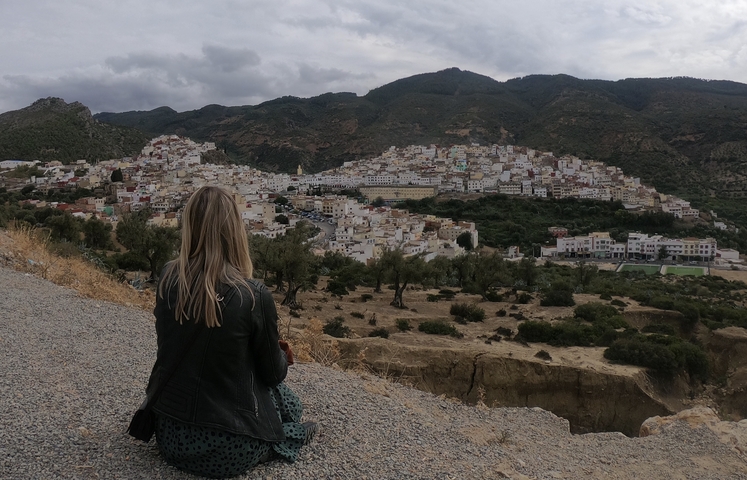       Woman looking over a town built into the hillsides.
  