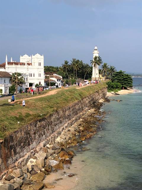       Lighthouse and coastline view with blue sky.
  