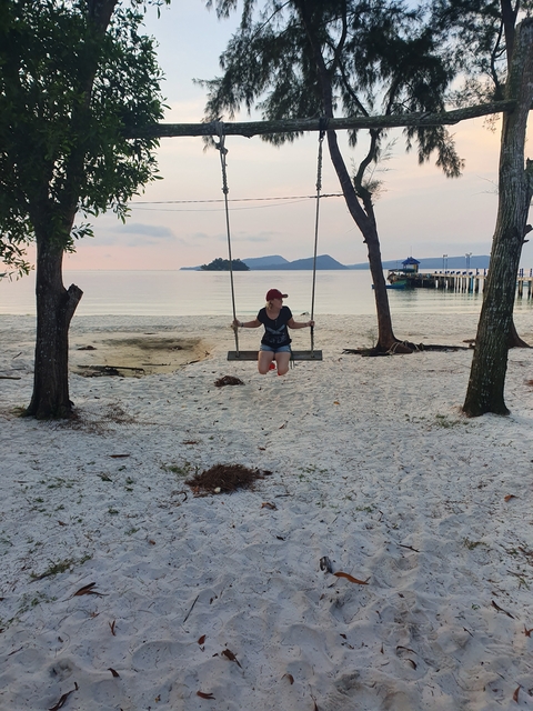 Person on a swing at the beach during sunset.