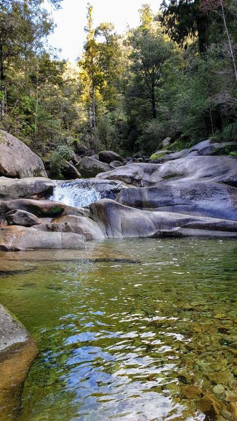 Calm pool of water with rocks and gentle cascade.