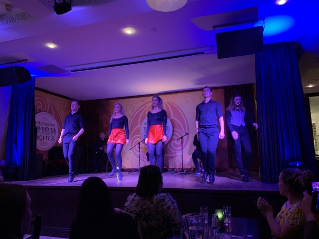 Dance performance on stage with five people in coordinated outfits.