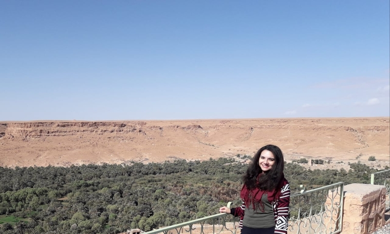       Woman posing with a scenic view of the desert and greenery.
  